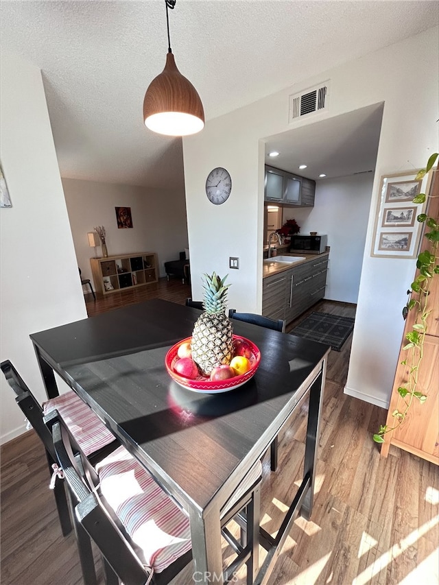 dining room featuring sink, hardwood / wood-style floors, and a textured ceiling