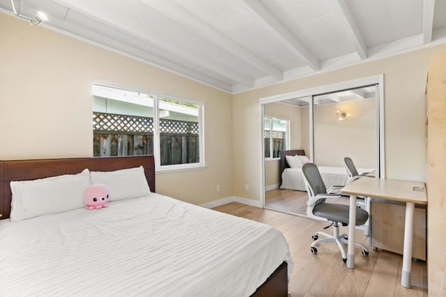 bedroom featuring beamed ceiling, light hardwood / wood-style floors, and a closet