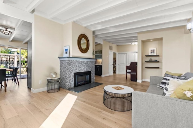 living room featuring hardwood / wood-style floors, a tile fireplace, and beamed ceiling