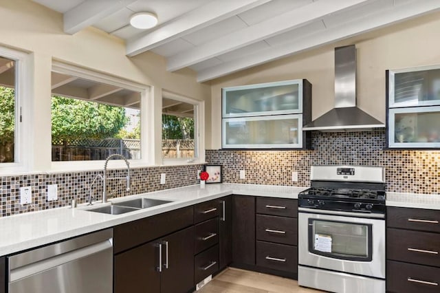 kitchen with stainless steel appliances, sink, wall chimney range hood, and dark brown cabinetry