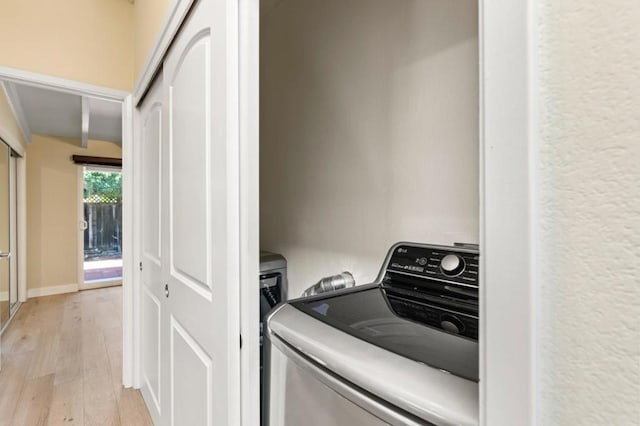 clothes washing area with washer / dryer and light hardwood / wood-style floors