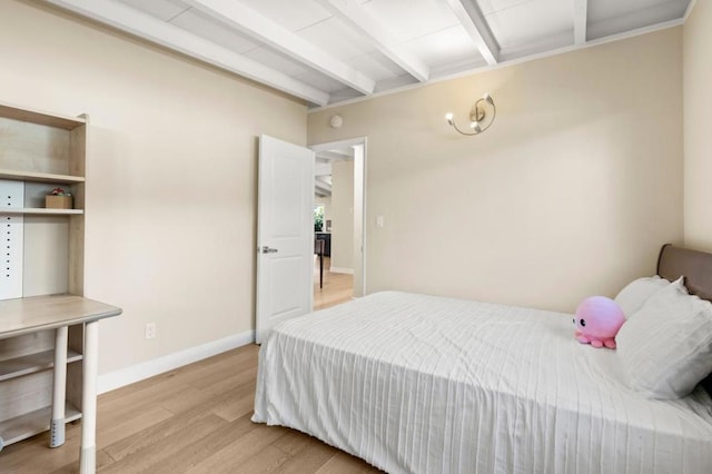 bedroom with beamed ceiling and light hardwood / wood-style floors