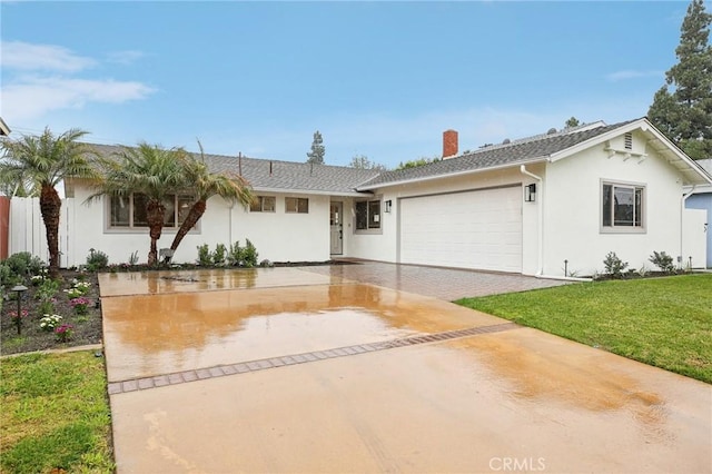 single story home with a garage, stucco siding, driveway, and a front lawn