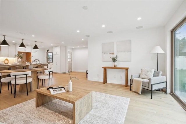 living room with recessed lighting, light wood-type flooring, and baseboards