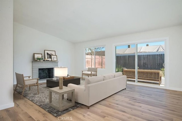 living room with a fireplace, vaulted ceiling, and light hardwood / wood-style flooring