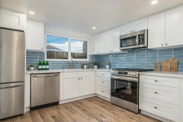 kitchen featuring white cabinetry, sink, stainless steel appliances, and light hardwood / wood-style floors