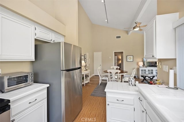 kitchen featuring stainless steel refrigerator, tile countertops, light hardwood / wood-style floors, and white cabinets