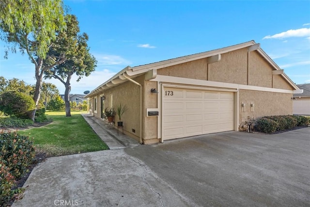 view of property exterior with a garage and a lawn