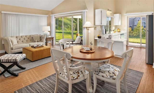 dining space featuring vaulted ceiling and light hardwood / wood-style floors