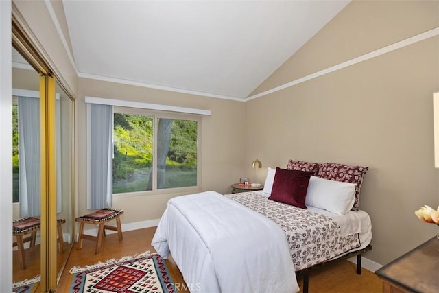 bedroom with a closet, lofted ceiling, wood-type flooring, and ornamental molding