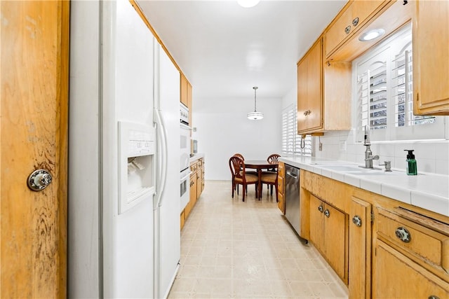 kitchen featuring sink, hanging light fixtures, white fridge with ice dispenser, stainless steel dishwasher, and tile counters