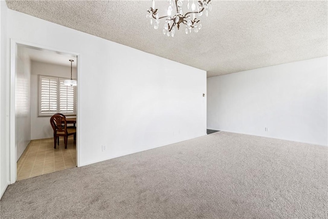 carpeted spare room with an inviting chandelier and a textured ceiling