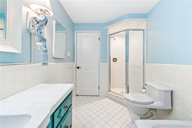 bathroom featuring an enclosed shower, vanity, tile walls, and tile patterned floors