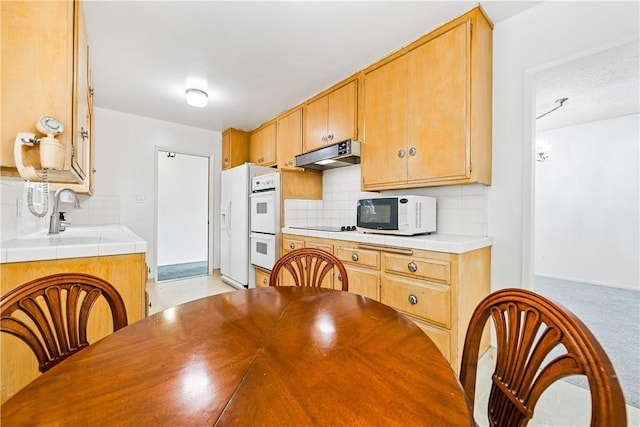 kitchen featuring tasteful backsplash, white appliances, tile counters, and sink