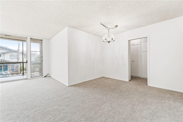 carpeted spare room with an inviting chandelier and a textured ceiling