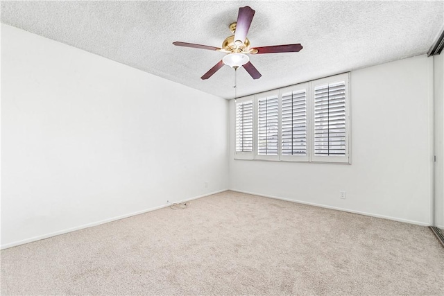 spare room with ceiling fan, light colored carpet, and a textured ceiling