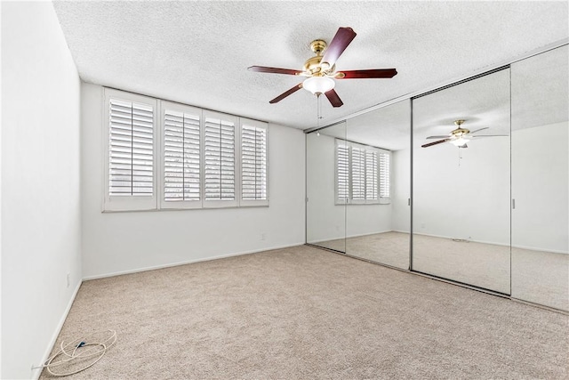 unfurnished bedroom with ceiling fan, carpet floors, a textured ceiling, and a closet