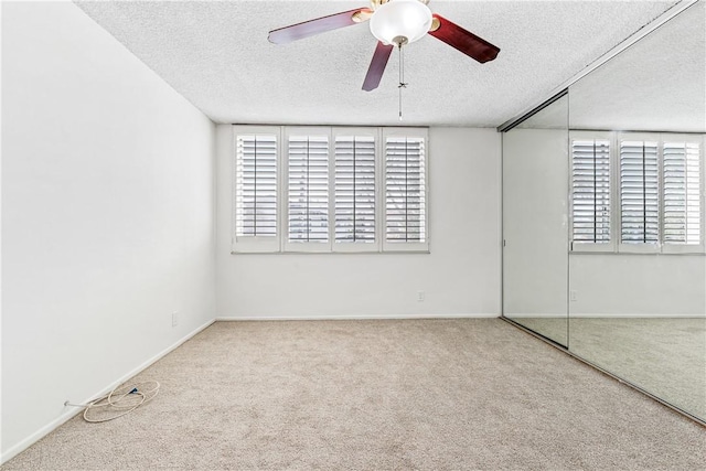 carpeted spare room with ceiling fan and a textured ceiling