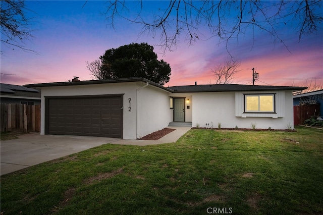 ranch-style home featuring a garage and a lawn