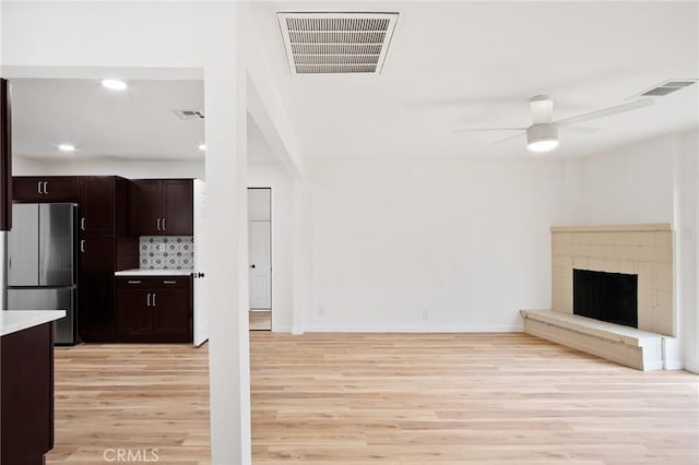 unfurnished living room featuring a brick fireplace, light wood-type flooring, and ceiling fan