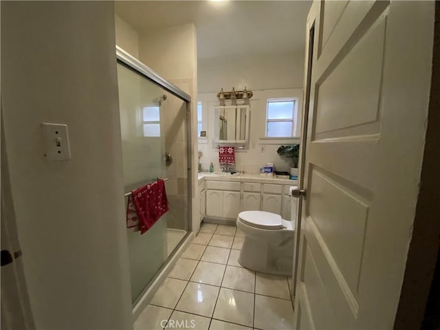 bathroom with toilet, vanity, tile patterned floors, and a shower with shower door