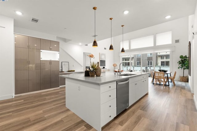 kitchen with sink, dishwasher, an island with sink, pendant lighting, and hardwood / wood-style floors