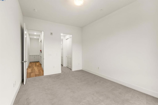 unfurnished bedroom with light carpet and a closet