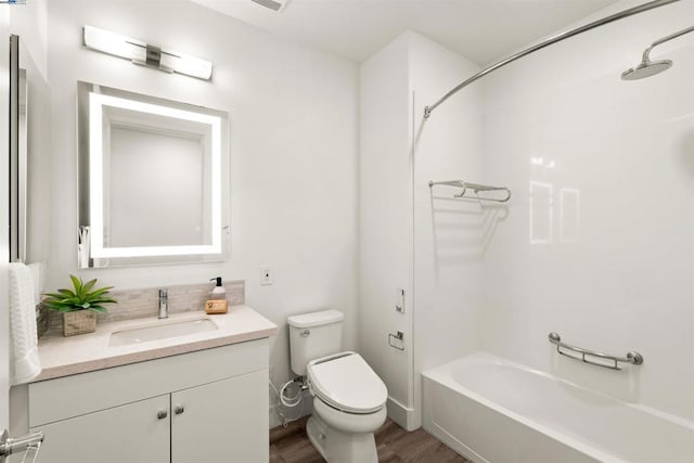 full bathroom with hardwood / wood-style flooring, washtub / shower combination, vanity, and toilet