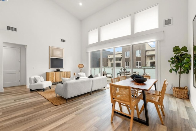 living room with a towering ceiling and light hardwood / wood-style floors