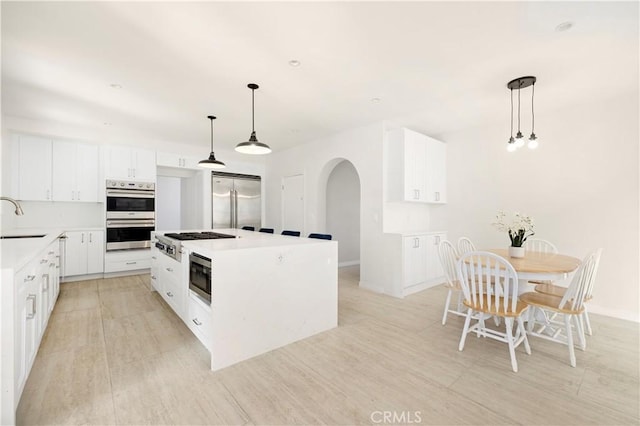 kitchen with sink, white cabinets, hanging light fixtures, a center island, and built in appliances