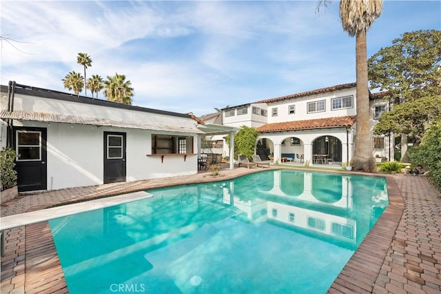 view of swimming pool featuring a patio and a diving board