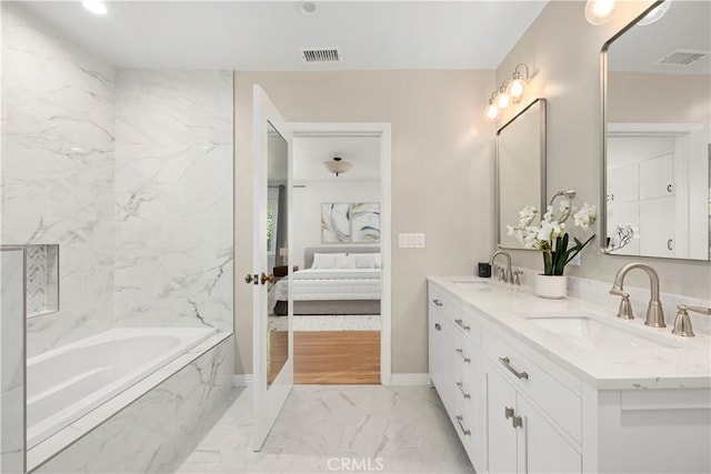 bathroom with tiled tub and vanity