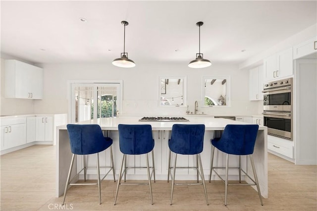 kitchen with sink, decorative light fixtures, a center island, stainless steel appliances, and white cabinets