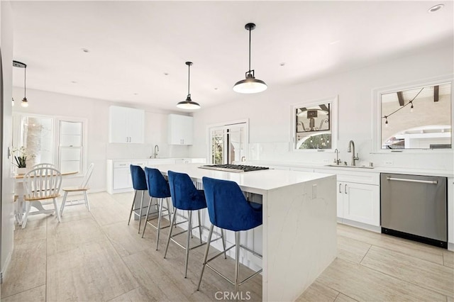 kitchen featuring a kitchen island, decorative light fixtures, white cabinetry, sink, and stainless steel appliances