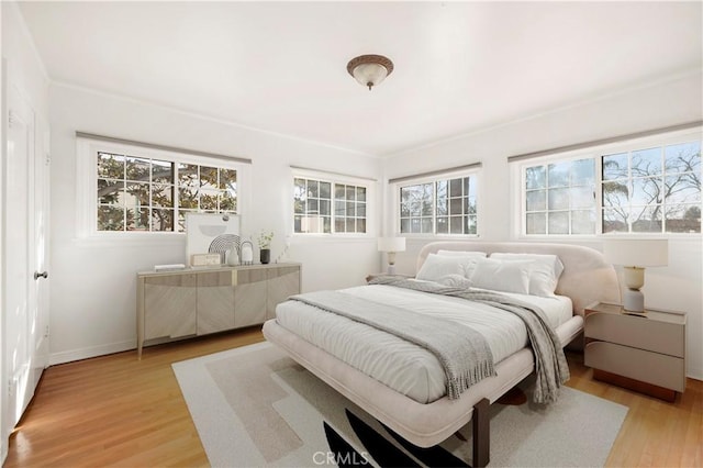 bedroom with multiple windows and light hardwood / wood-style flooring