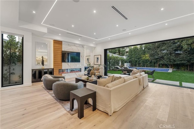 living room with a high end fireplace and light hardwood / wood-style flooring