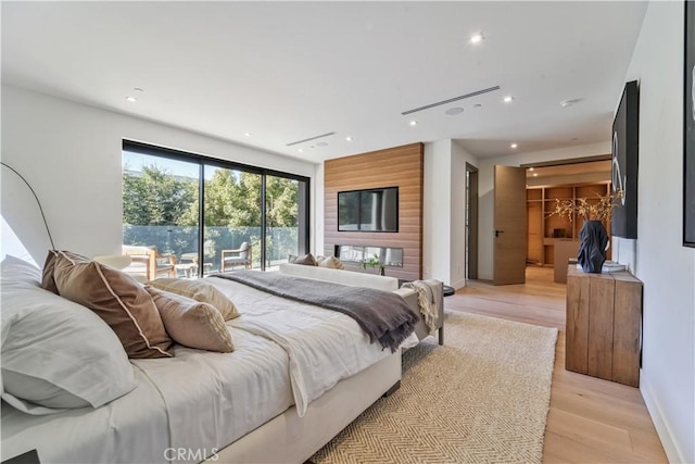 bedroom with a spacious closet, access to exterior, and light wood-type flooring