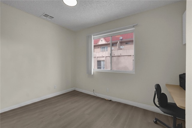 unfurnished office featuring hardwood / wood-style flooring and a textured ceiling