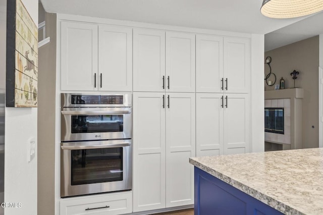 kitchen with blue cabinetry, stainless steel double oven, and white cabinets