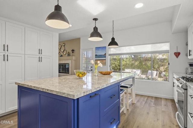 kitchen featuring blue cabinets, white cabinetry, a center island, hanging light fixtures, and stainless steel stove