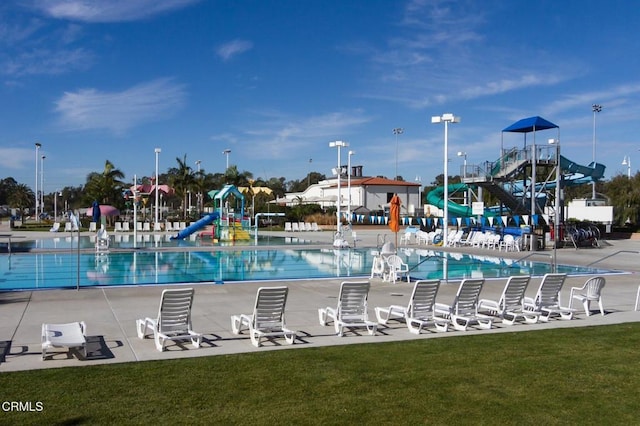 view of swimming pool with a yard and a playground