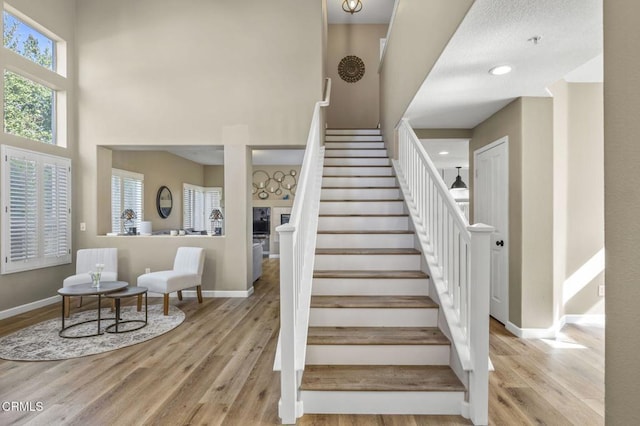 stairs with hardwood / wood-style floors and a high ceiling