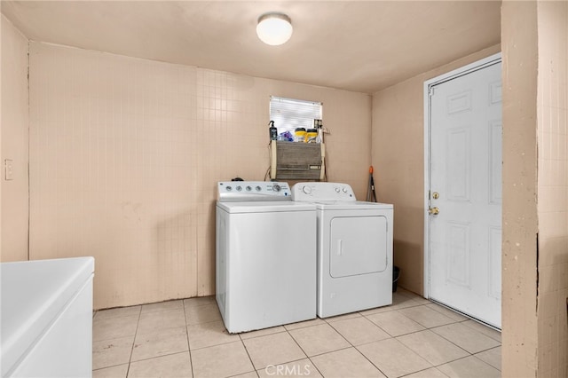 laundry area featuring washing machine and dryer, light tile patterned floors, and tile walls