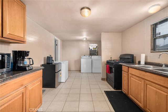 kitchen featuring sink, light tile patterned floors, appliances with stainless steel finishes, tasteful backsplash, and washer and dryer