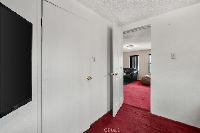 corridor with dark carpet and a textured ceiling