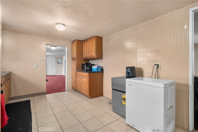 kitchen featuring fridge, tile walls, and light tile patterned floors