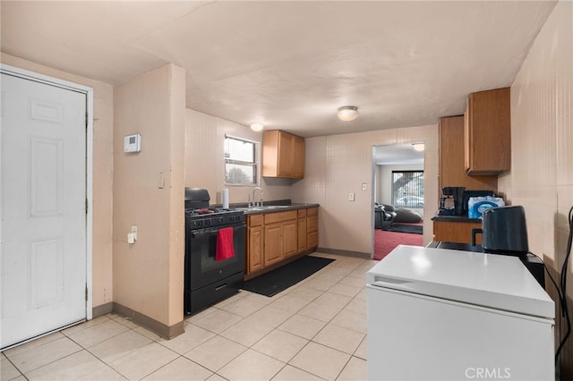 kitchen with light tile patterned flooring, black gas range oven, and sink