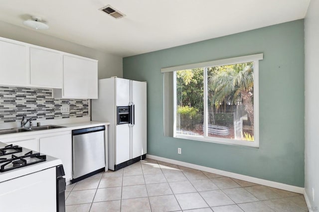 kitchen featuring sink, white appliances, tasteful backsplash, white cabinets, and light tile patterned flooring