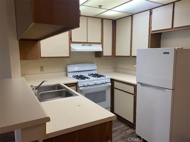 kitchen with sink, white cabinets, dark hardwood / wood-style flooring, kitchen peninsula, and white appliances