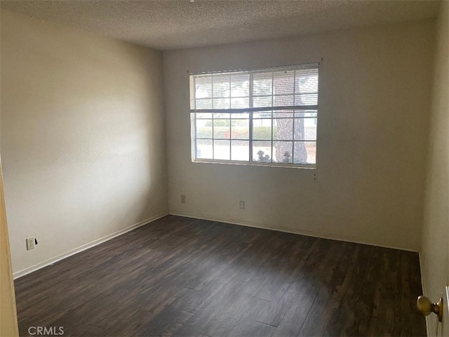 unfurnished room with dark wood-type flooring and a textured ceiling